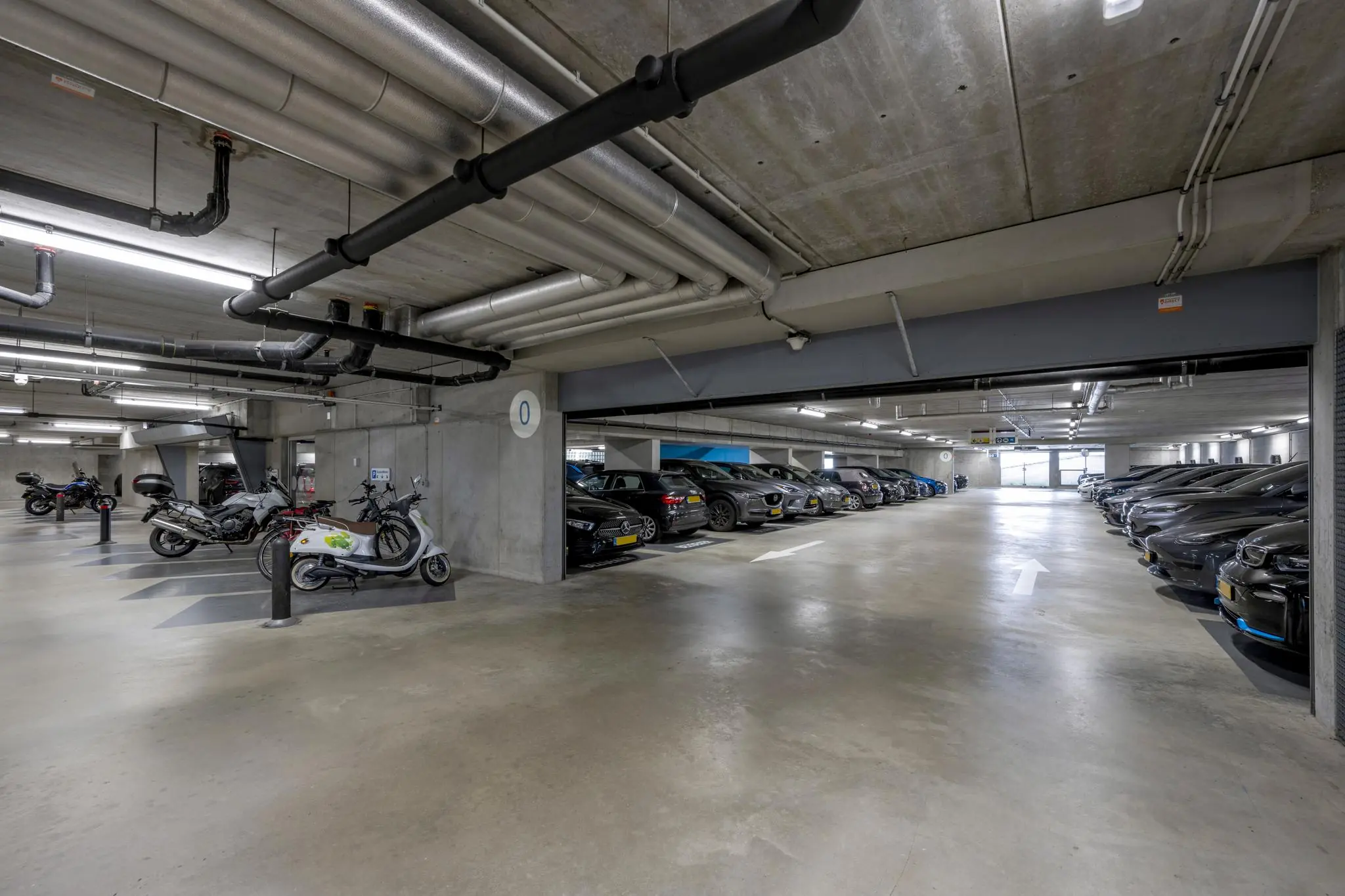 Ondergrondse parkeergarage Airportplein in Rotterdam met geparkeerde auto's en scooters.